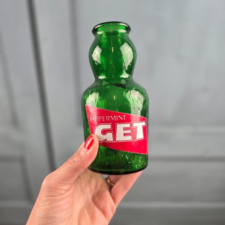 Bouteille publicitaire GET 27 ancienne verre vert Pippermint vintage, tenue en main pour montrer la taille