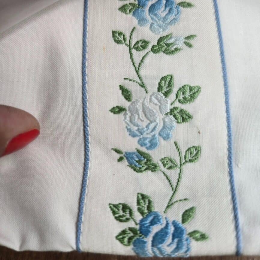 Ensemble drap plat et taie traversin coton fleurs bleues vintage, zoom sur le textile et la broderie