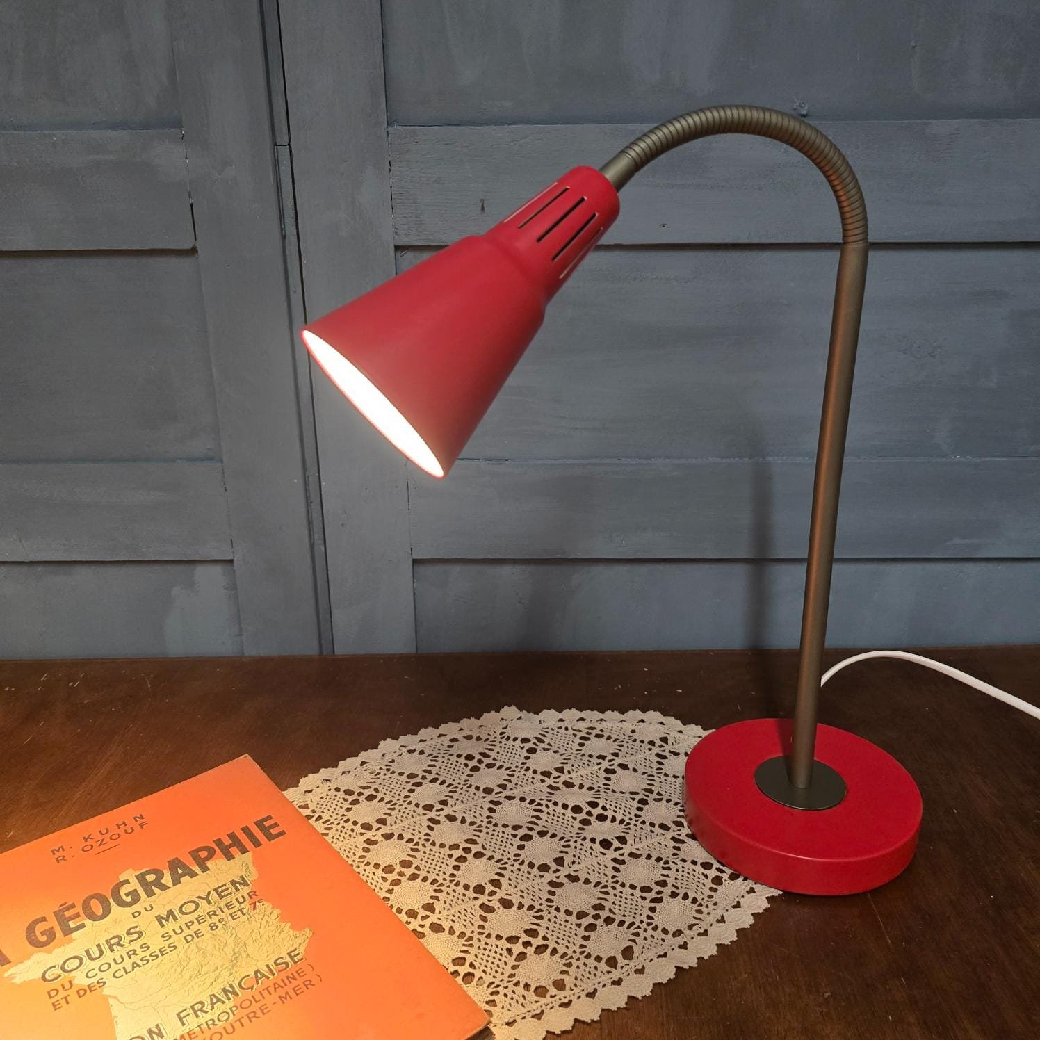 Lampe de bureau IKEA Kvart rouge, design Hagberg, allumée sur table en bois