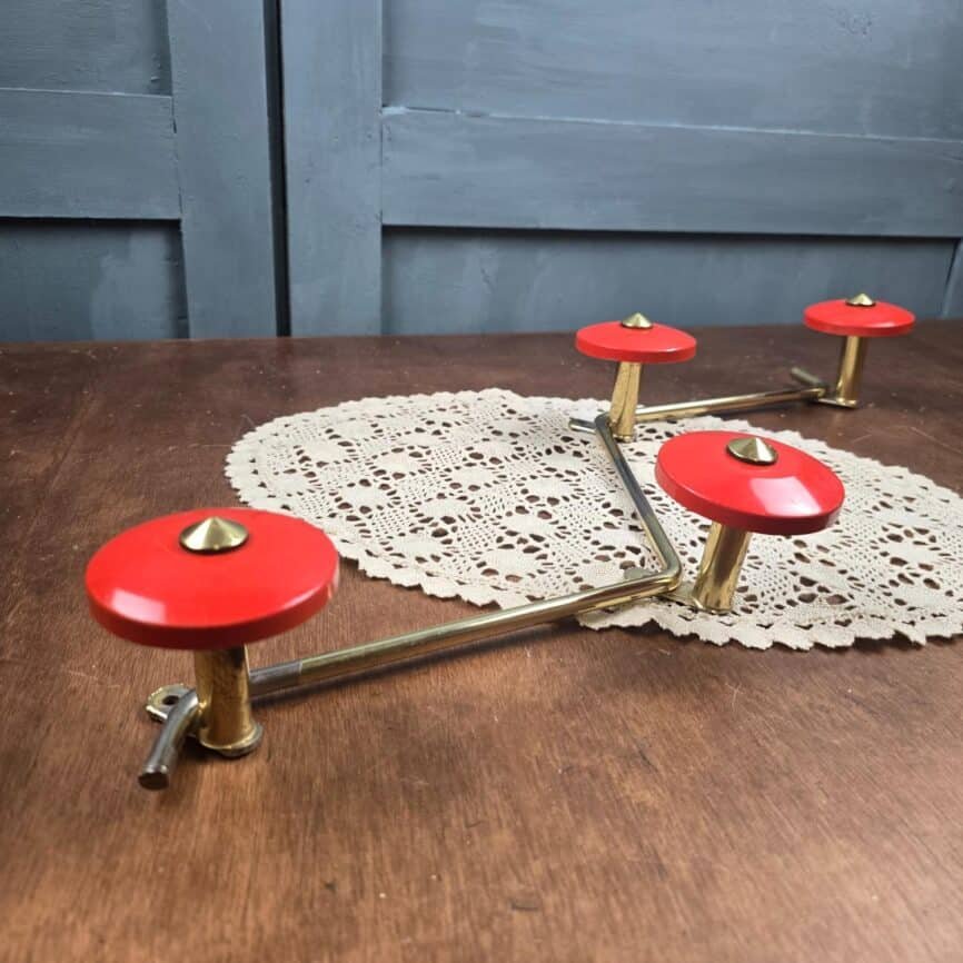 Porte-manteau mural vintage zig-zag rouge orangé et doré années 60 posé sur table en bois