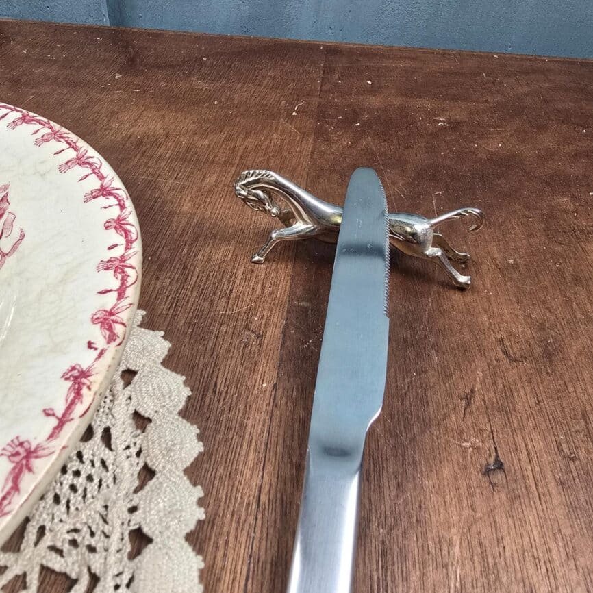 Repose-couteaux en forme de cheval galopant vintage en métal argenté mise en situation sur table en bois