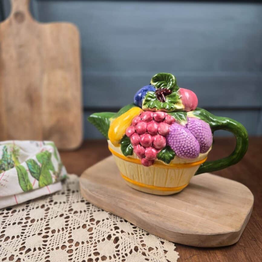 Théière vintage corbeille de fruits style barbotine – Céramique fruits en relief ambiance vintage, fond flouté