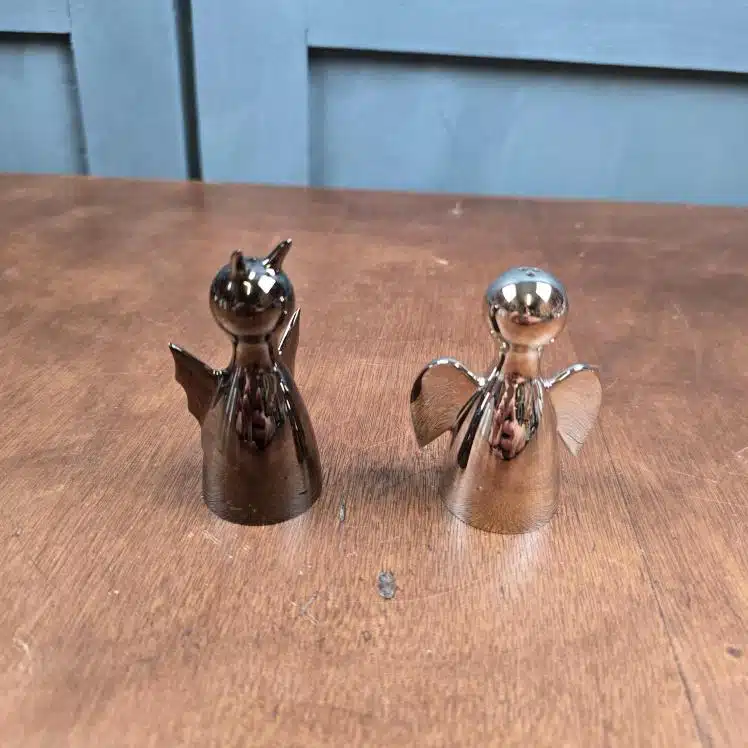 Set salière poivrière ange et démon Philippi Joyas Design métal argenté sur table en bois