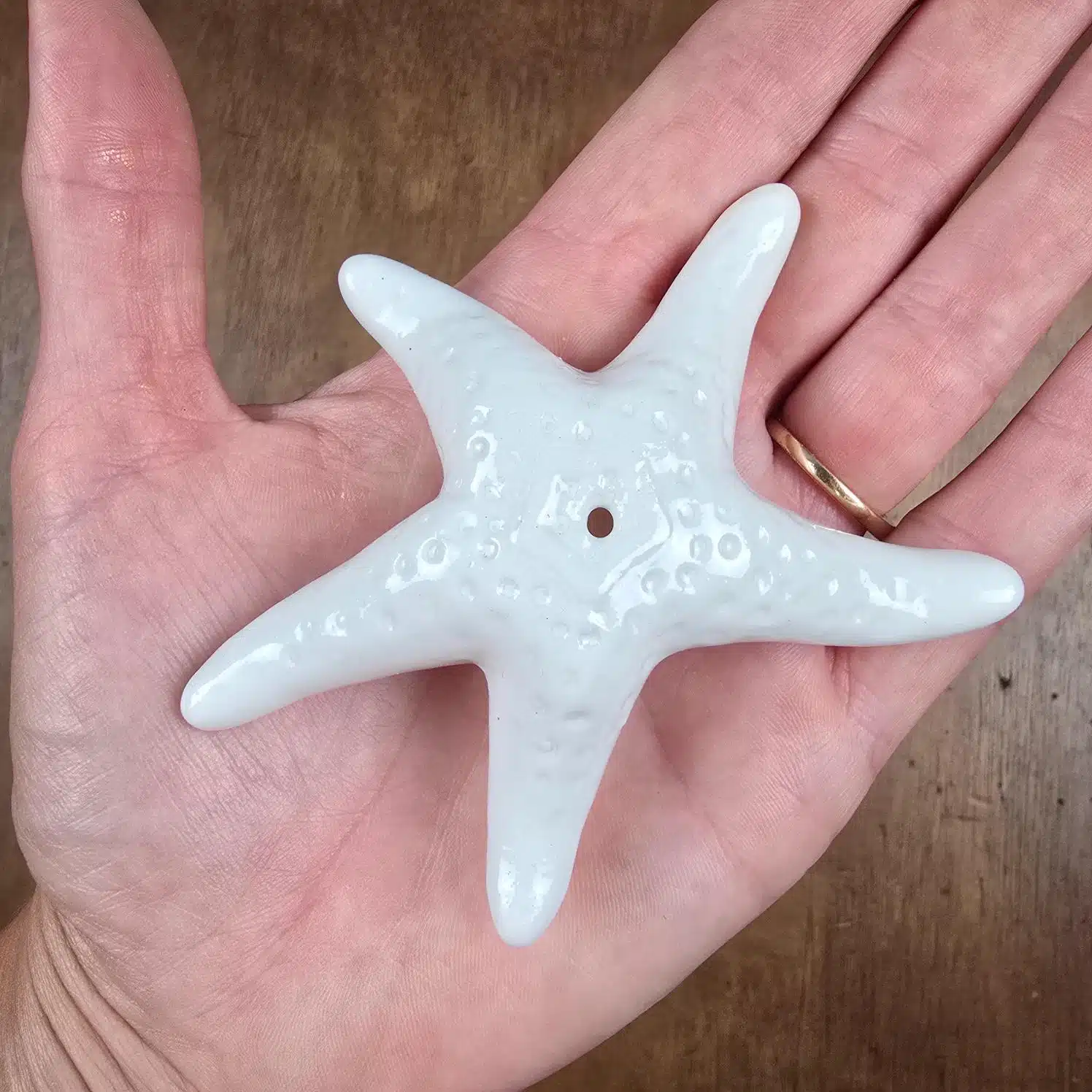 Poivrière en forme d'étoile de mer en céramique blanche tenue en main