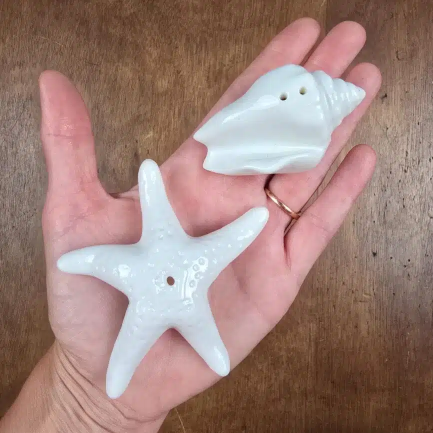 Set salière poivrière coquillage et étoile de mer en céramique blanche tenue en main pour mesure