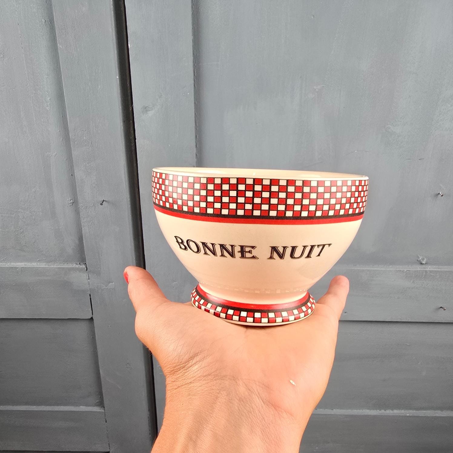 Bol bonne nuit Linvosges motif damier rouge et noir rétro, posé en main pour apprécier la mesure