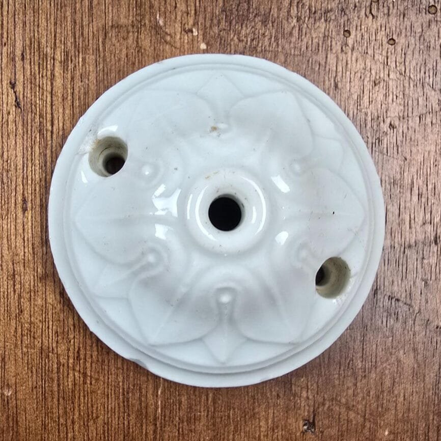 Rosace de plafond ancienne en porcelaine blanche vue de dessus sur table en bois