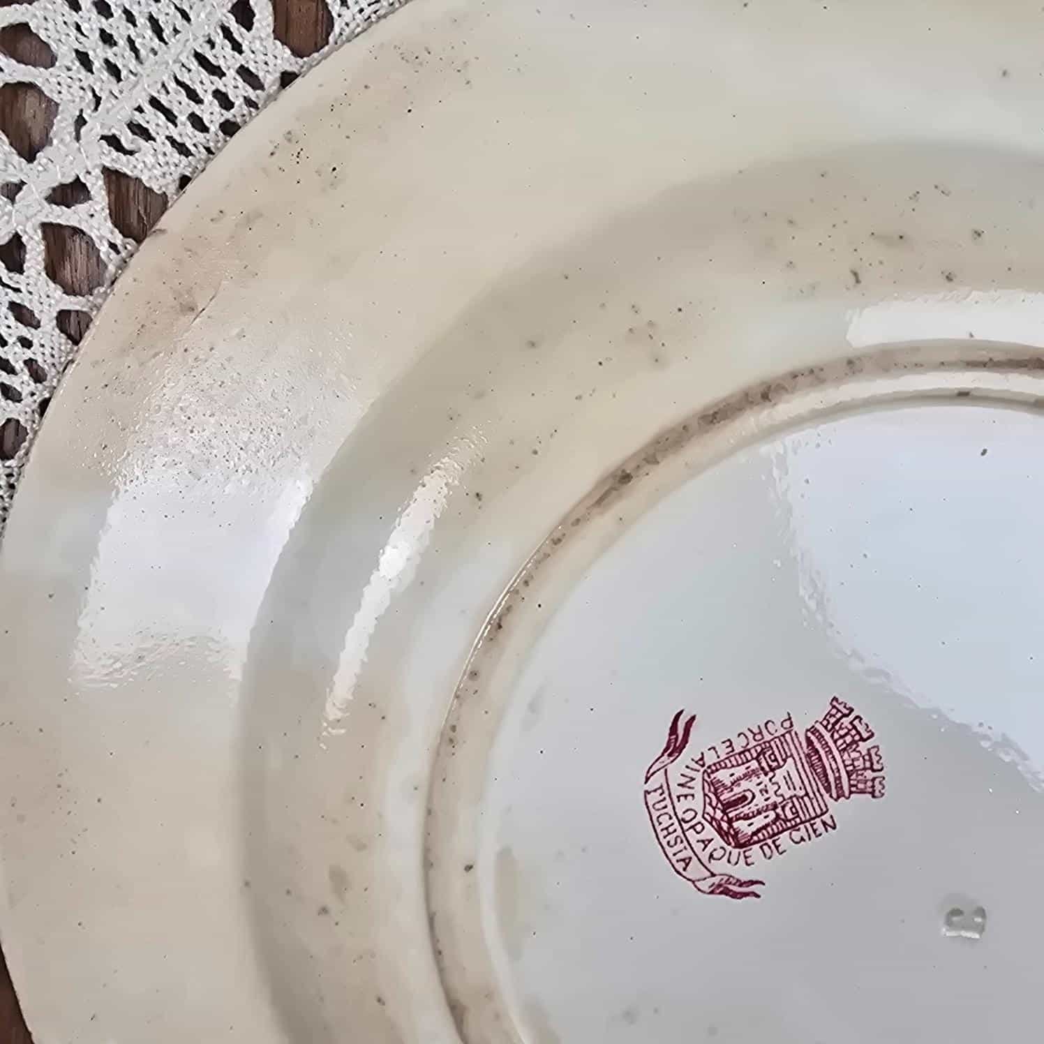 Zoom du dos d'une assiette ancienne Gien montrant les tâches et la texture