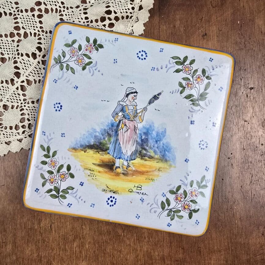 Dessous-de-plat HB Quimper ancien, décor bretonne à la quenouille, vue de dessus sur table en bois et napperon
