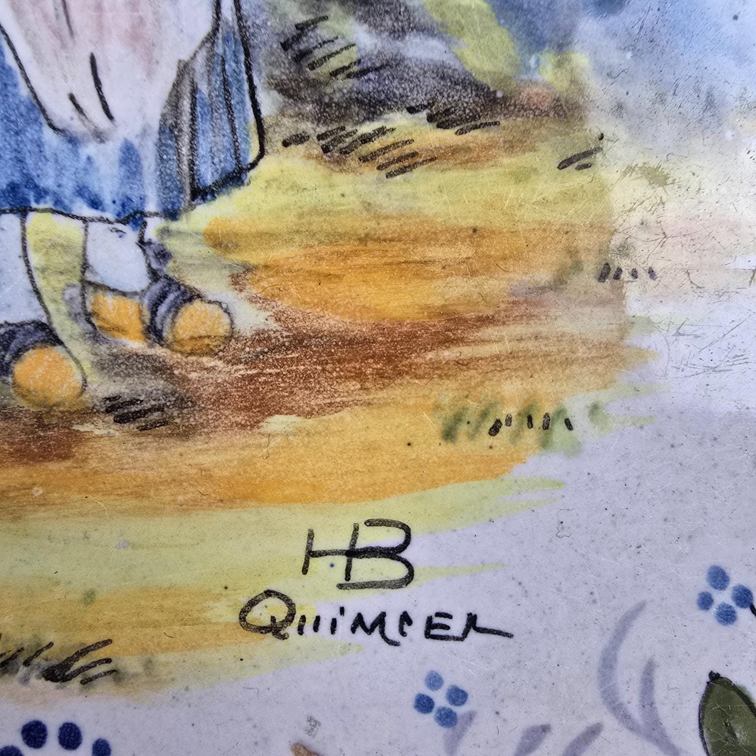 Dessous-de-plat HB Quimper ancien, décor bretonne à la quenouille, zoom sur la signature en bas du dessin