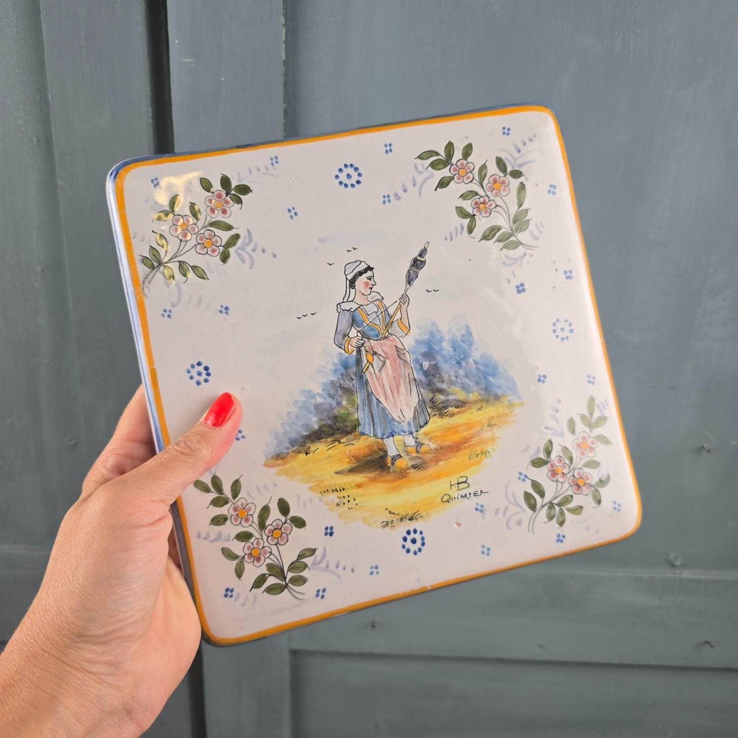 Dessous-de-plat HB Quimper ancien, décor bretonne à la quenouille, tenu en main pour mesure
