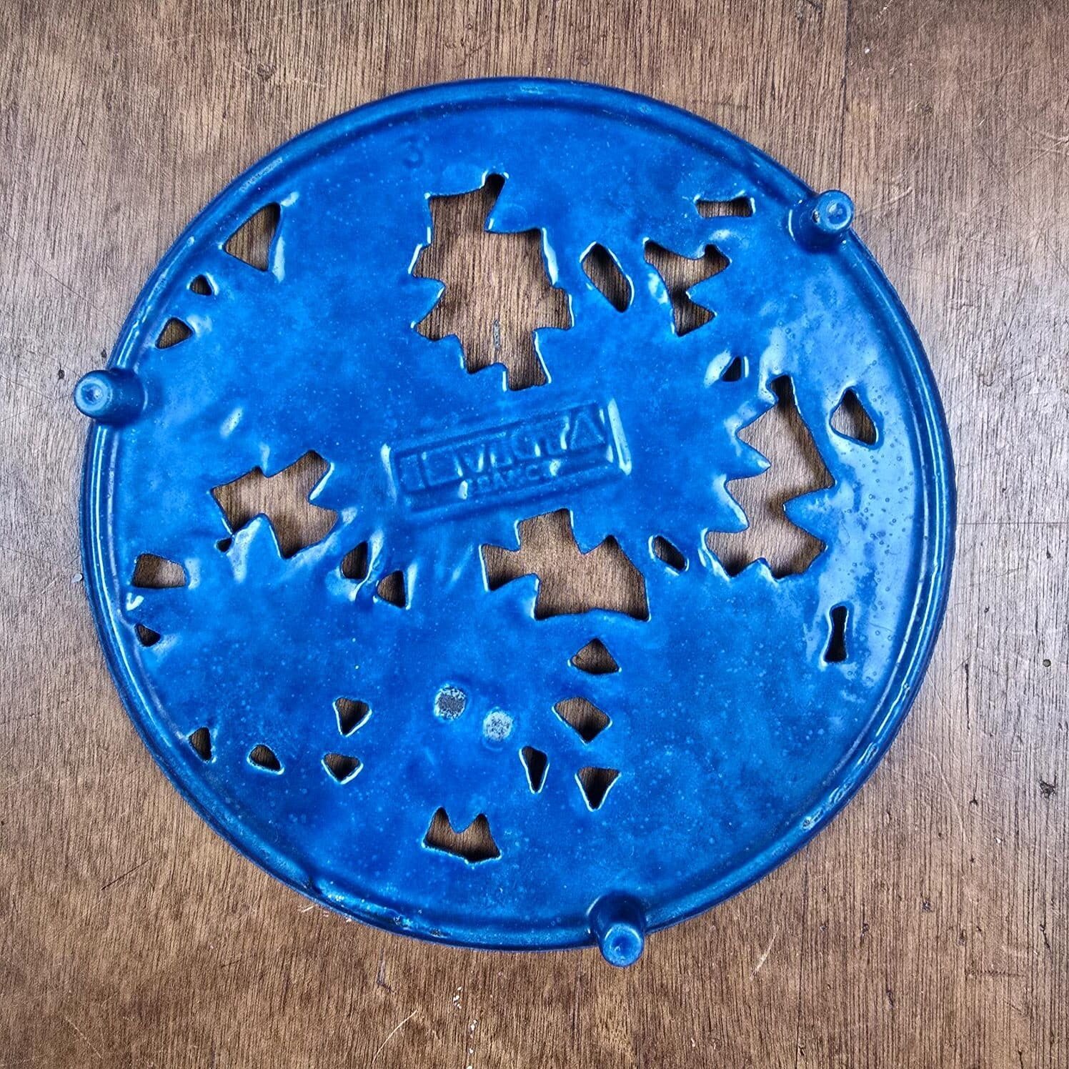 Dessous de plat en fonte émaillée bleue à fleurs Invicta vue dessous sur table en bois