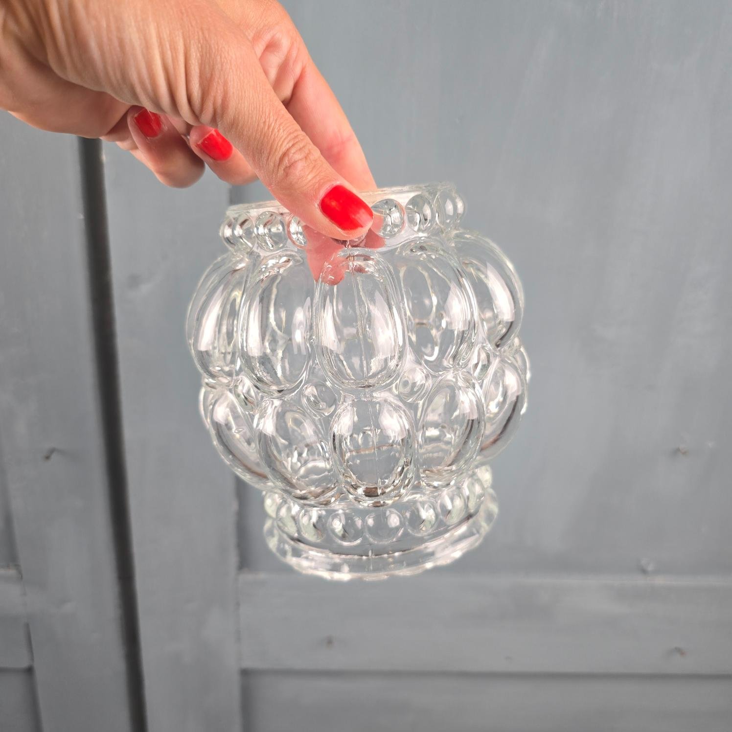 Globe en verre moulé transparent tenu en main pour montrer le luminaire suspendu