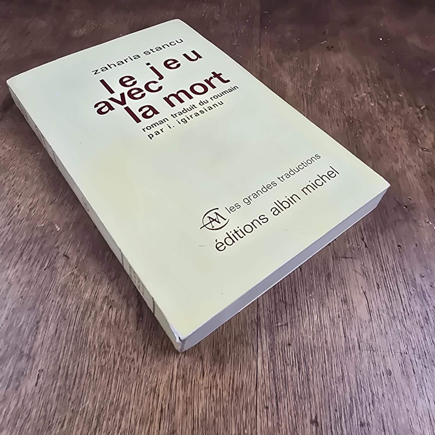 Vue plongeante de la couverture du livre Le Jeu avec la mort, Zaharia Stancu – Les Grandes Traductions, Albin Michel 1964, sur table en bois