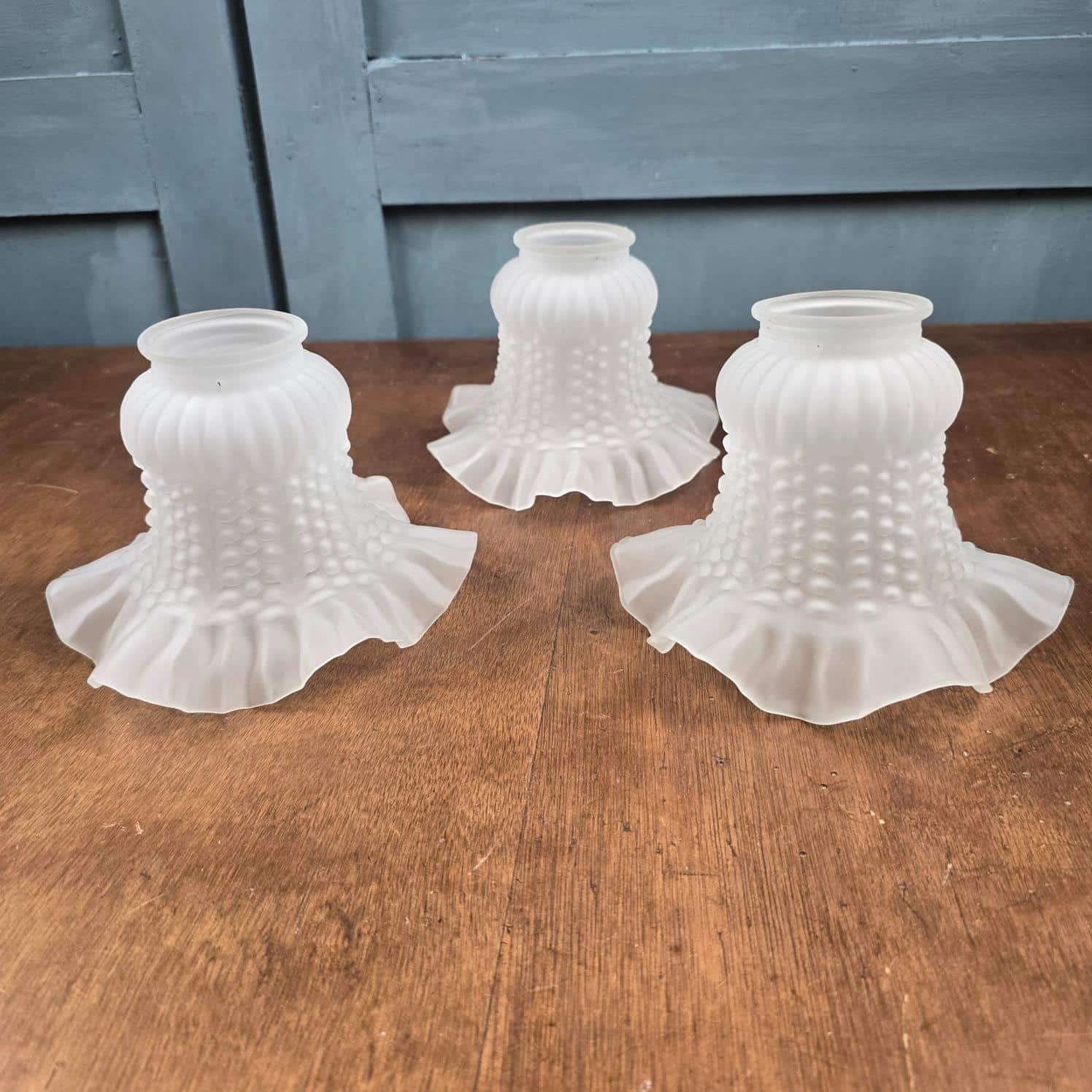 Lot de 3 tulipes anciennes en verre satiné pour luminaire – Décor perlé et plissé sur table en bois