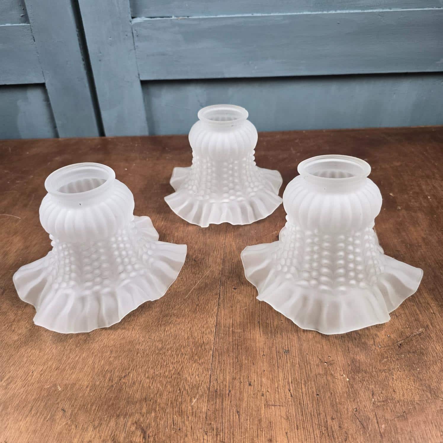 Lot de 3 tulipes anciennes en verre satiné pour luminaire – vue de côté sur table en bois