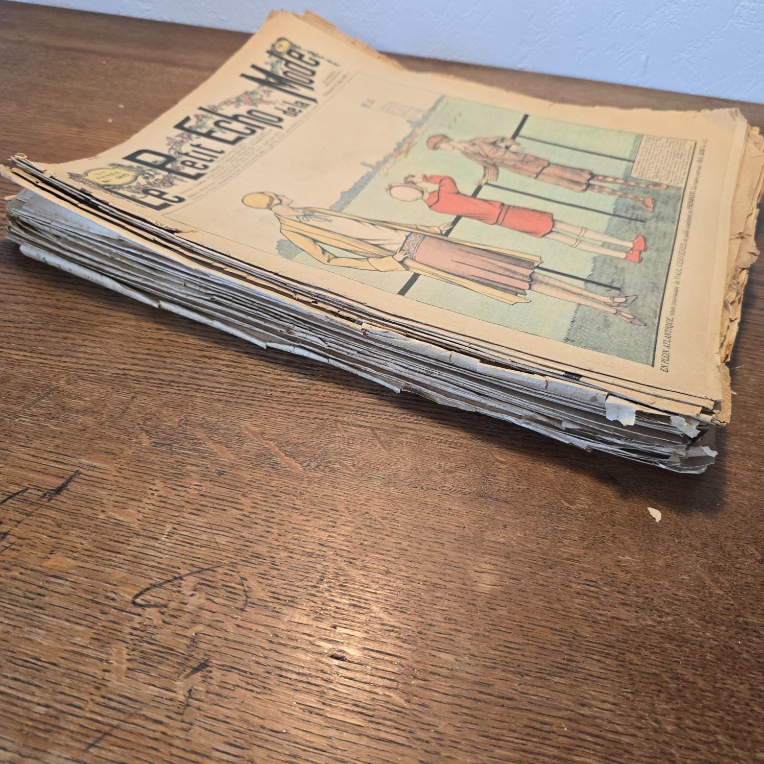 Lot de 29 magazines « Le Petit Écho de la Mode », 1922 à 1928, vue de côté, sur table en bois