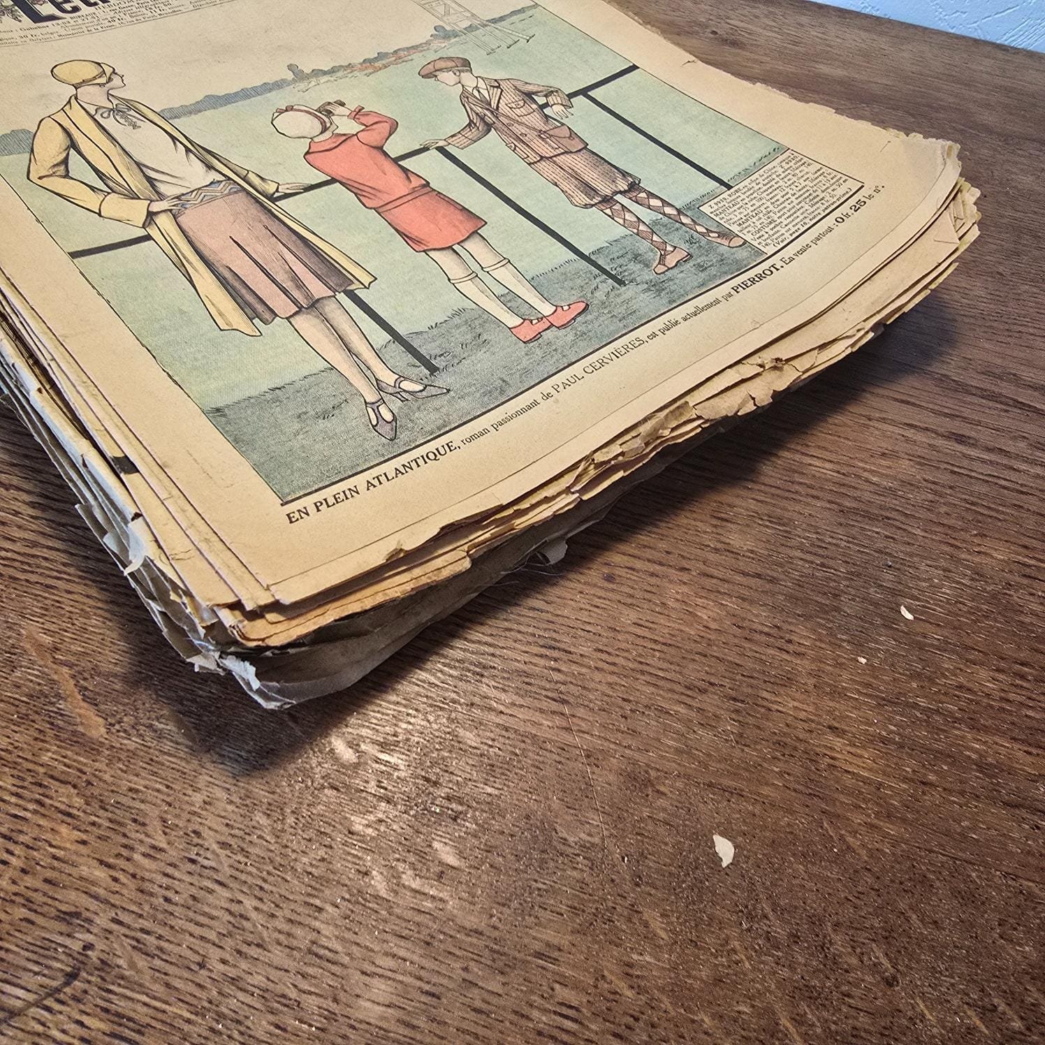 Lot de 29 magazines « Le Petit Écho de la Mode », 1922 à 1928, vue de la tranche du bas, sur table en bois