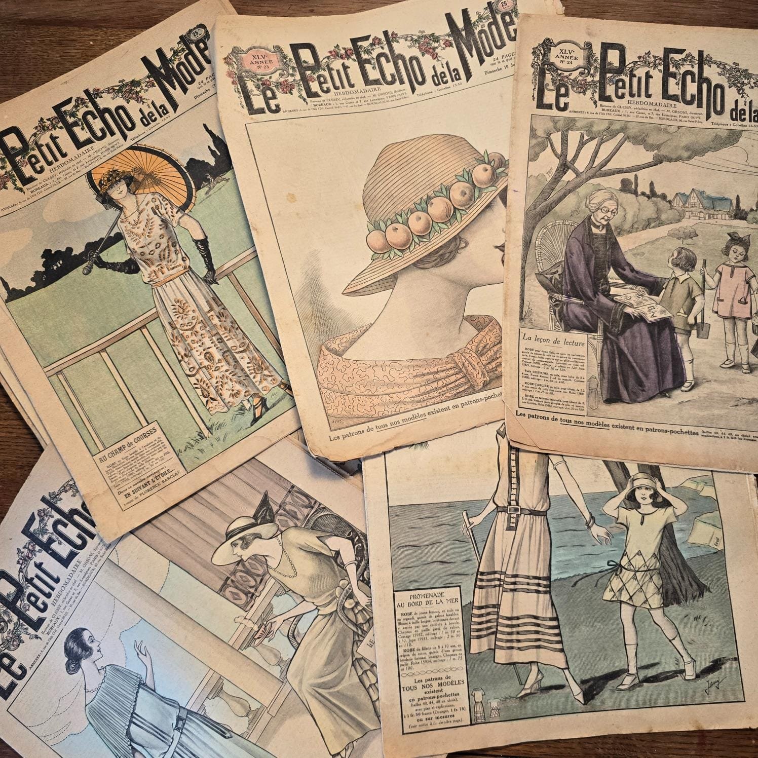 Magazines « Le Petit Écho de la Mode » sur table en bois