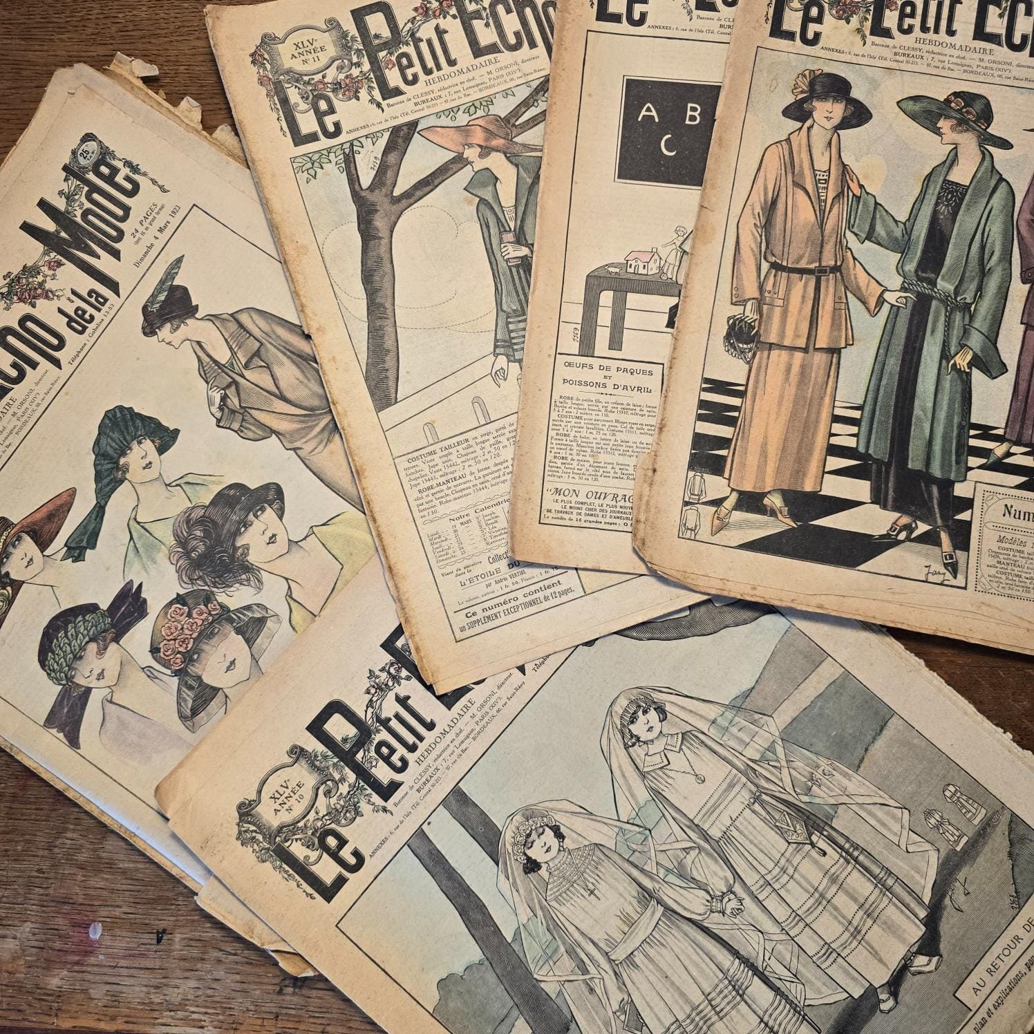 Magazines « Le Petit Écho de la Mode » des années folles vus de dessus sur table en bois