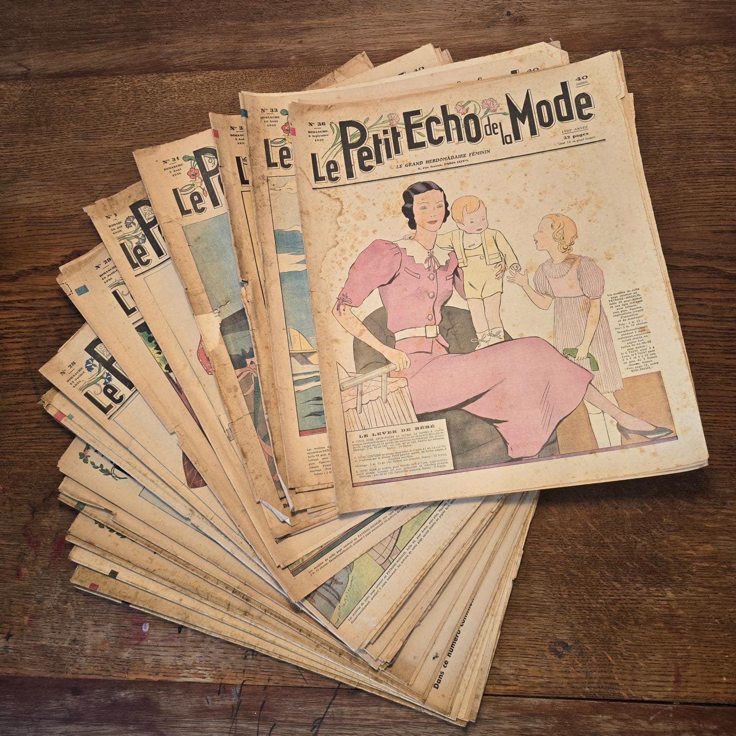 Lot de 30 « Le Petit Écho de la Mode », 1936 – Magazines féminins anciens, étalés sur table en bois