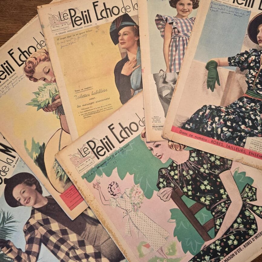 Lot de 35 « Le Petit Écho de la Mode » de 1938, étalé sur une table en bois, mettant en avant les jolies couvertures colorées