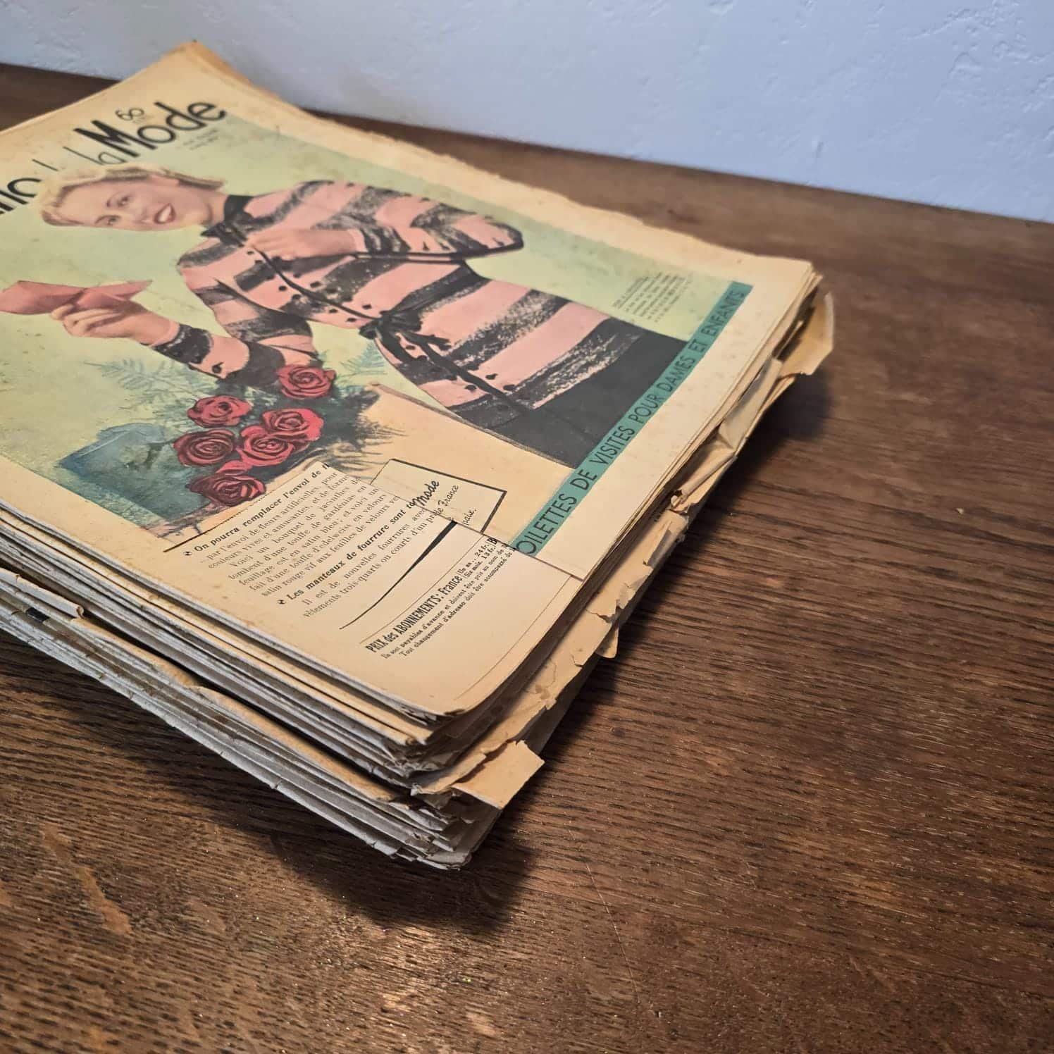 Lot de 35 « Le Petit Écho de la Mode » de 1938, en tas sur une table en bois, vue de la tranche du bas