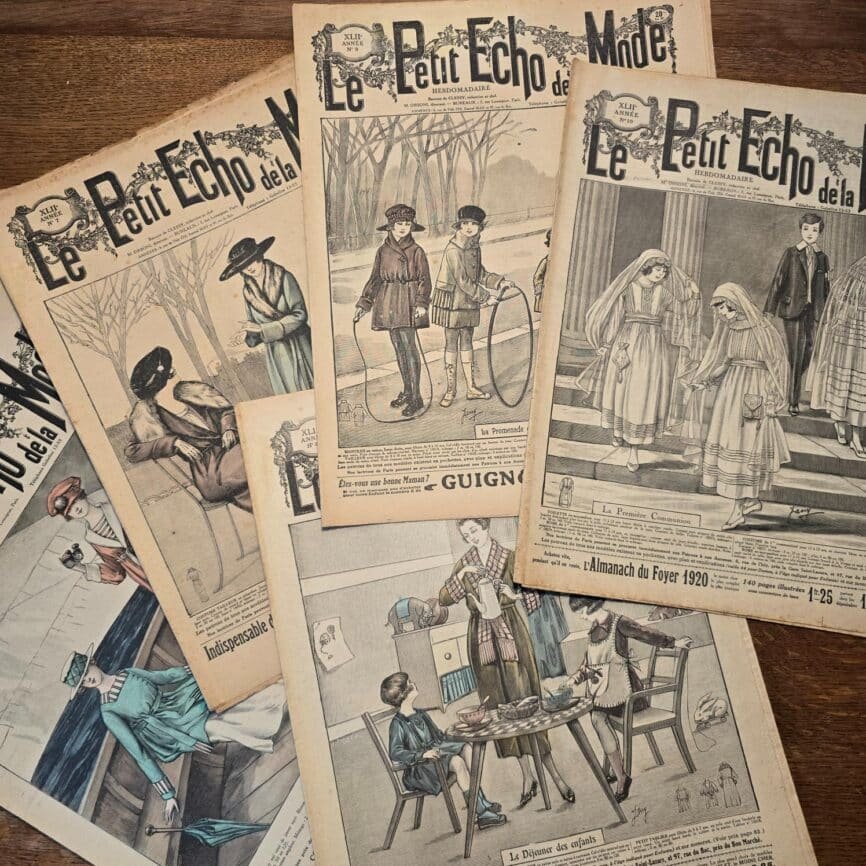 Ensemble de magazines « Le Petit Écho de la Mode » étalés sur table en bois, vue de dessus, couvertures en noir & blanc