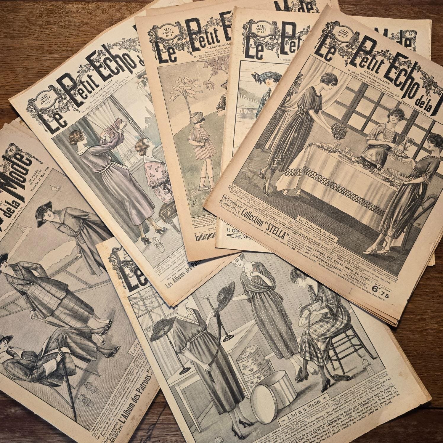 Ensemble de magazines « Le Petit Écho de la Mode » des années 30, vue de dessus sur table en bois