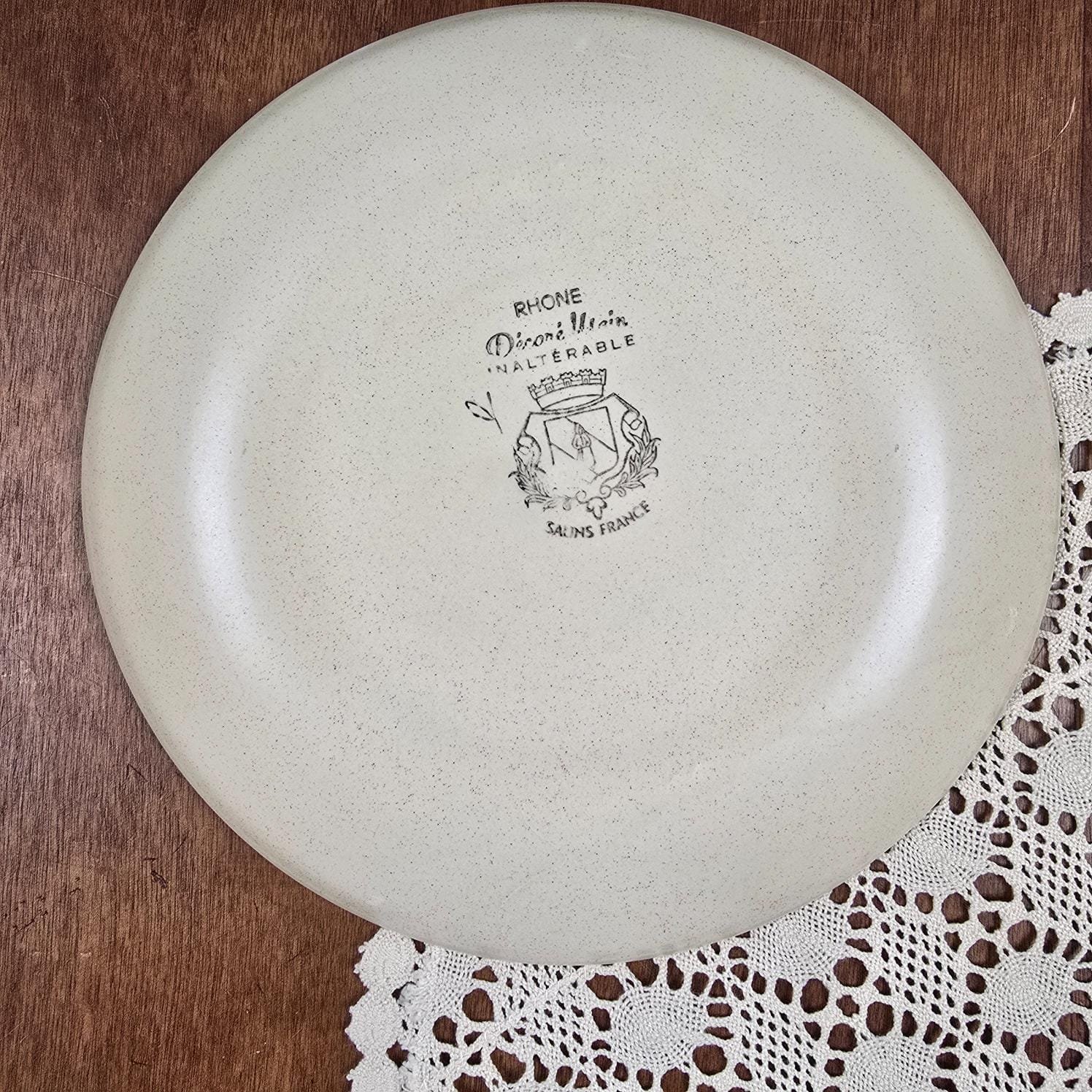 sDessous d'une assiette Salins, modèle Rhône montrant l'estampille "Décor main, inaltérable, Salins France" et le nom du modèle RHONE
