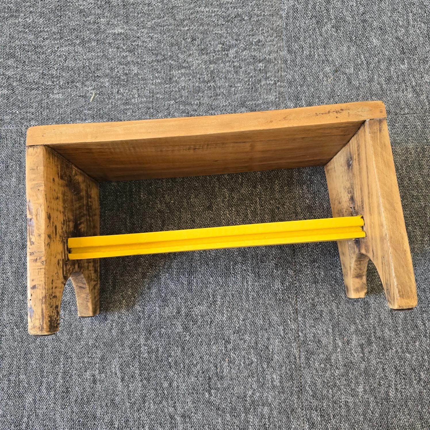 Petit tabouret ancien artisanal en bois, vue de côté mettant en avant la traverse jaune moutarde