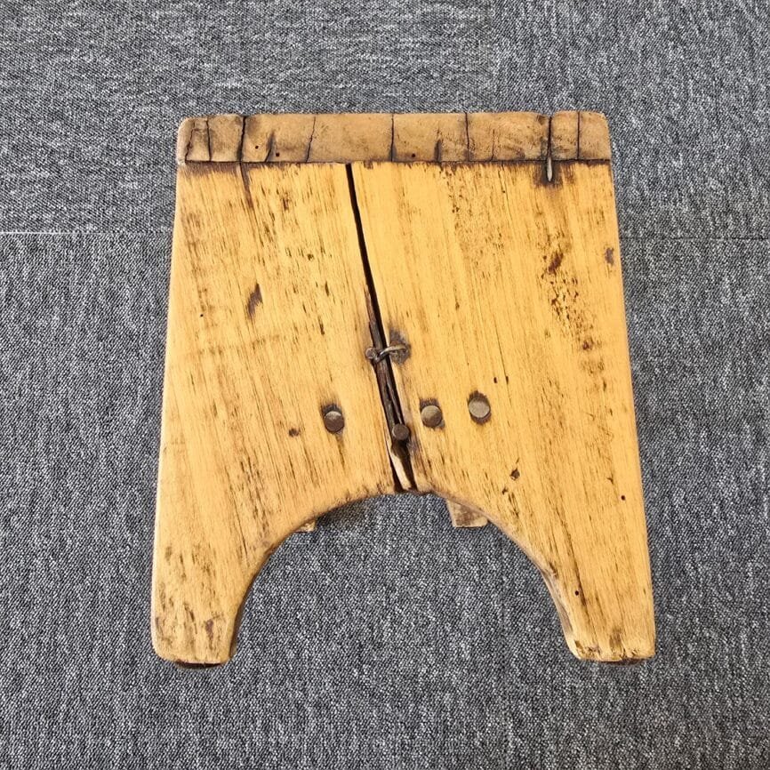 Petit tabouret ancien artisanal en bois, vue de côté mettant en avant les nombreux clous