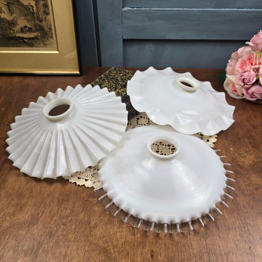 Composition de trois abat-jour vintage en verre opalin blanc sur une table en bois