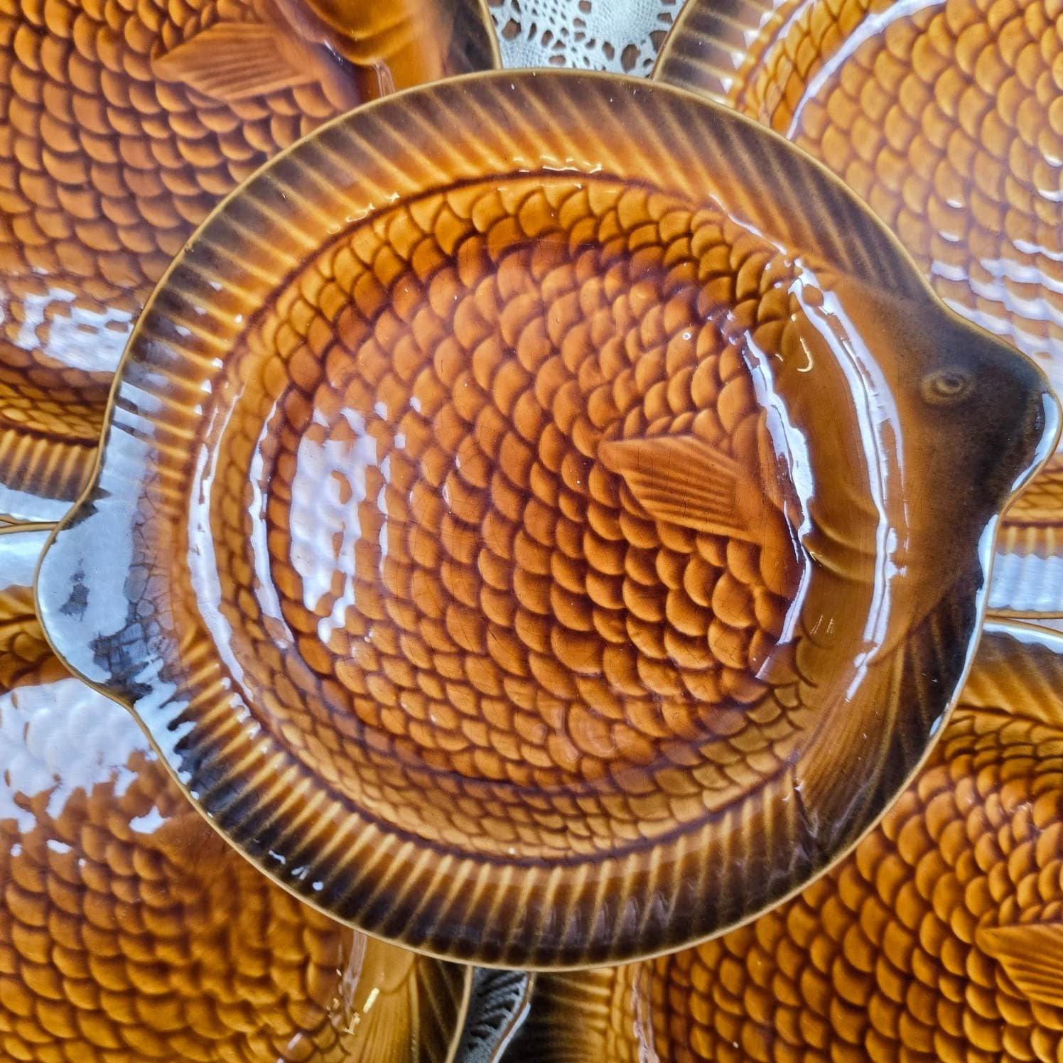 Gros plan sur les écailles en relief et la glaçure brillante d’une assiette poisson caramel