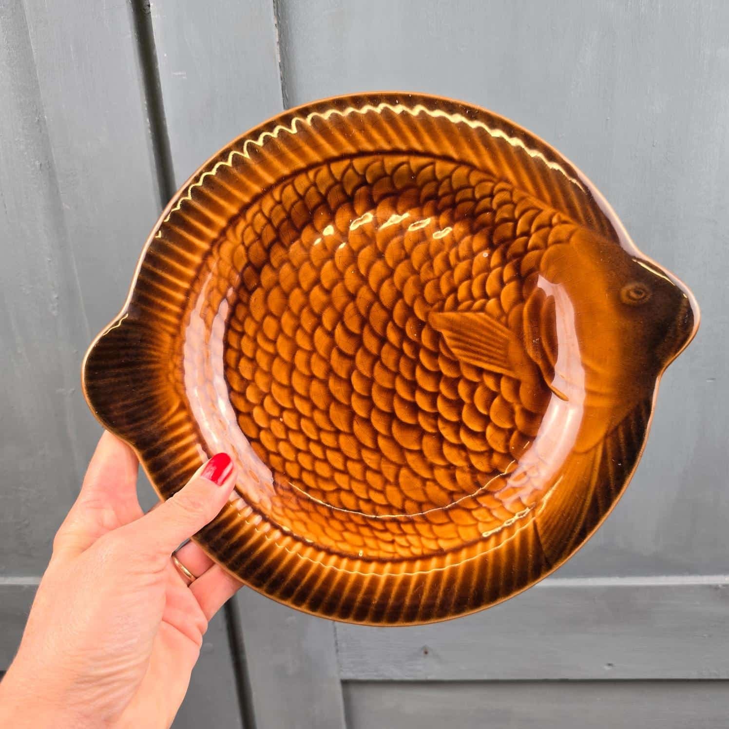 Assiette poisson Sarreguemines tenue à la main, montrant sa forme et ses nageoires