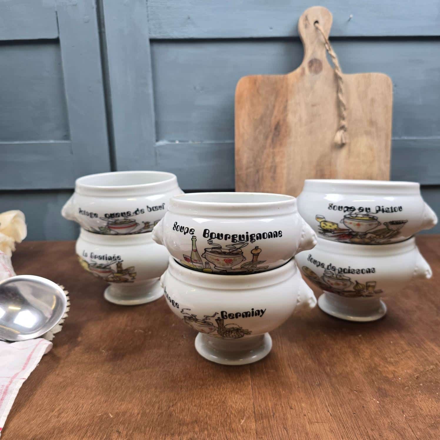 Ensemble de six bols à soupe vintage en porcelaine blanche, décorés de recettes françaises, sur une table en bois