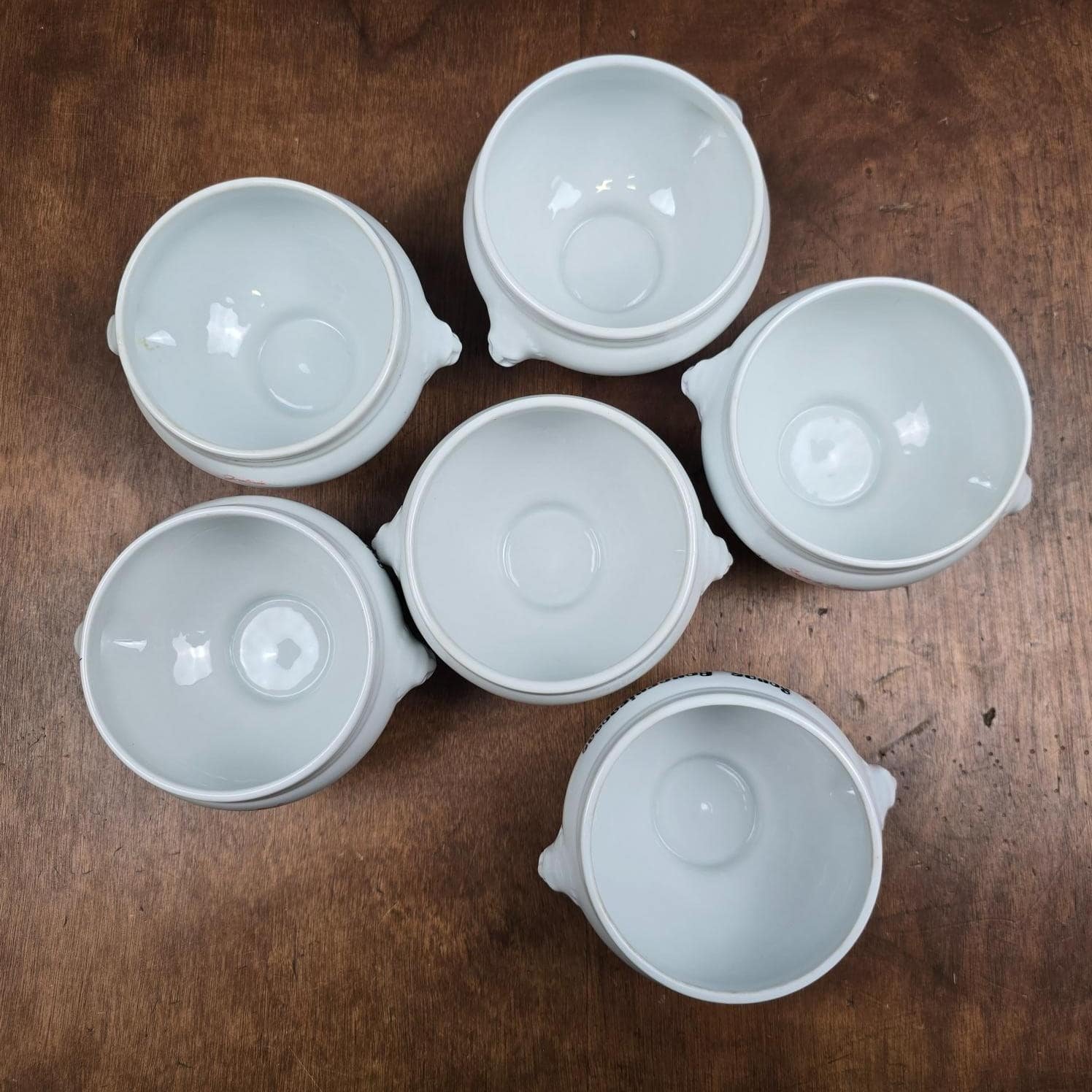 Vue du dessus des six bols en porcelaine blanche montrant leur intérieur et leurs deux anses