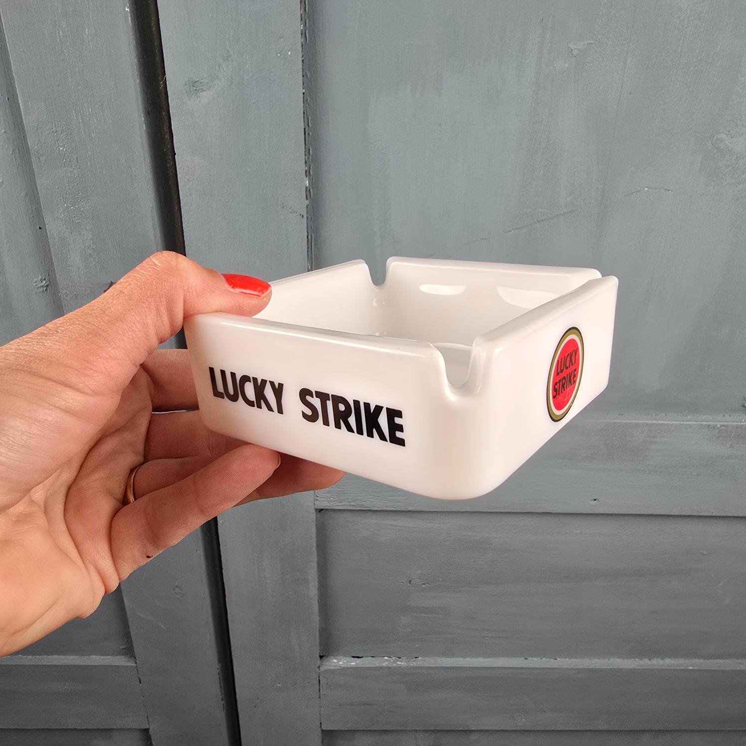 Cendrier publicitaire vintage Lucky Strike en verre opalin, made in France, tenu en main pour mesure
