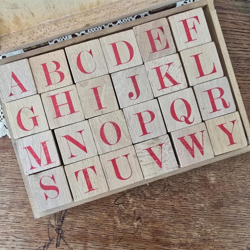 Vue rapprochée des cubes alphabet Jeujura, lettres rouges rangées dans la boîte en bois