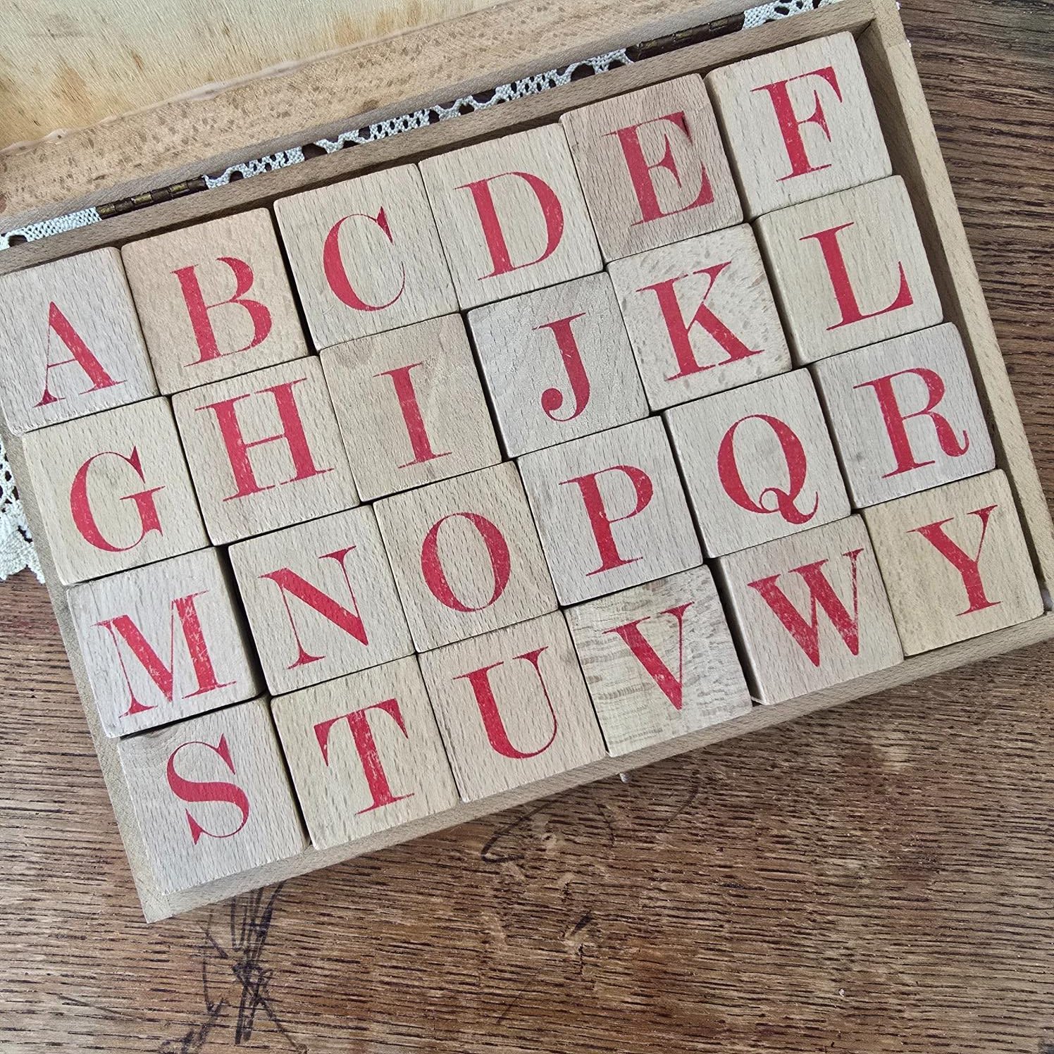 Vue rapprochée des cubes alphabet Jeujura, lettres rouges rangées dans la boîte en bois