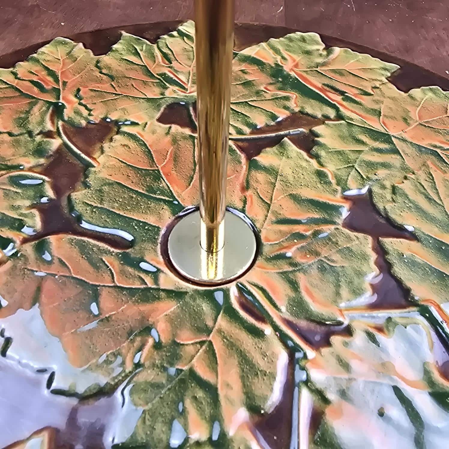Détail de la fixation de la poignée dorée au centre du décor de feuilles de vigne