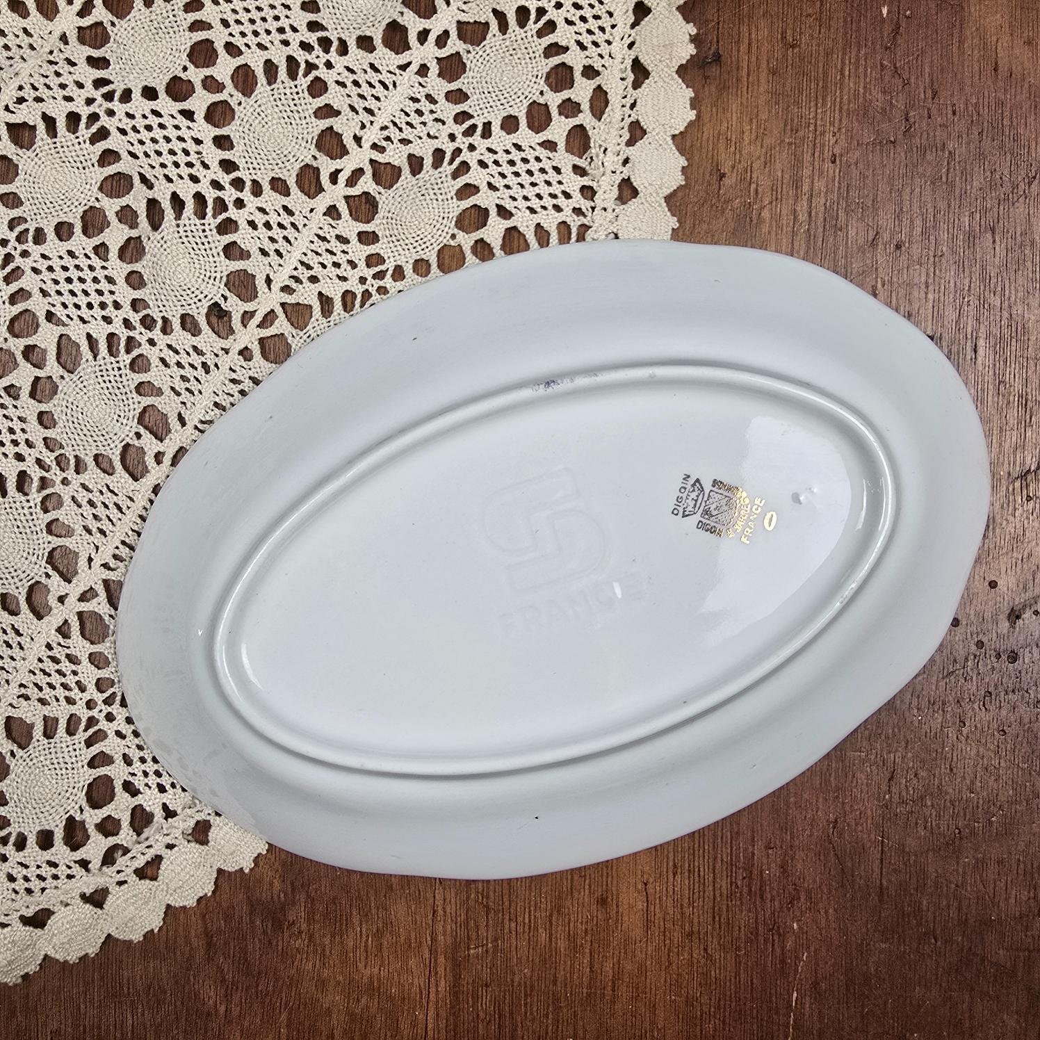Dessous du ravier ovale Digoin Sarreguemines posé sur une nappe en dentelle