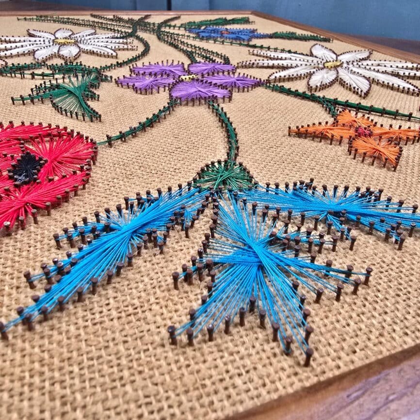 Vue rapprochée du tableau en string art avec fleurs rouges, bleues et blanches
