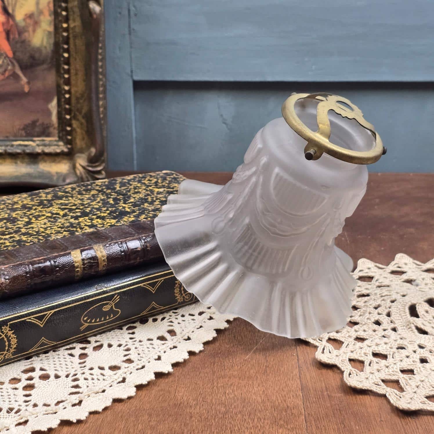 Abat-jour tulipe en verre dépoli à bordure plissée et griffe dorée, mise en scène avec livres anciens