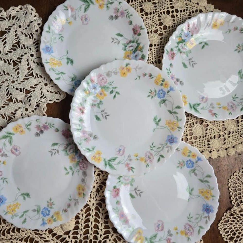 Lot de 4 assiettes Arcopal Hortense disposées sur des napperons en dentelle, vue de dessus.