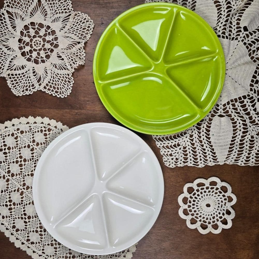 Assiettes Le Creuset verte et blanche posées sur une table avec napperons crochet vintage