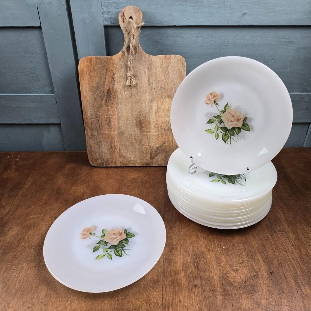 Ensemble de 12 assiettes Arcopal à décor de roses, présentées empilées sur table en bois