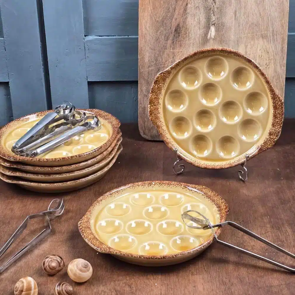 Lot de 6 assiettes à escargots Gien brun miel avec pinces en inox sur fond en bois.