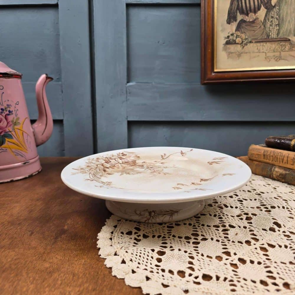 Plat ancien sur pied décor sépia – faïence Terre de Fer À la Pâquerette Paris, vue de côté.