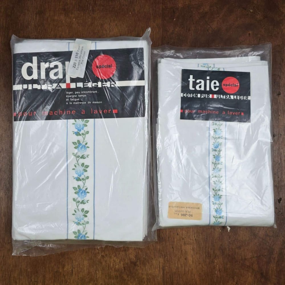 Ensemble drap plat 220x310 et taie traversin coton fleurs bleues vintage vue de dessus sur table en bois, neuf